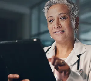 Mature professional woman with short gray hair using a tablet device indoors.