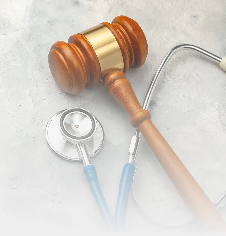 Wooden judge's gavel and blue stethoscope on a light gray textured surface.