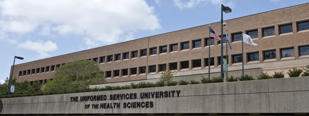 Exterior view of The Uniformed Services University of the Health Sciences building with flags and blue sky.