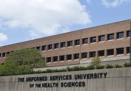 Exterior view of a multi-story brick university building with "The Uniformed Services University of the Health Sciences" sign.