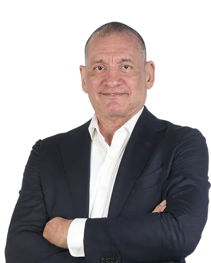 Middle-aged man with short hair wearing a dark suit and white shirt, arms crossed.