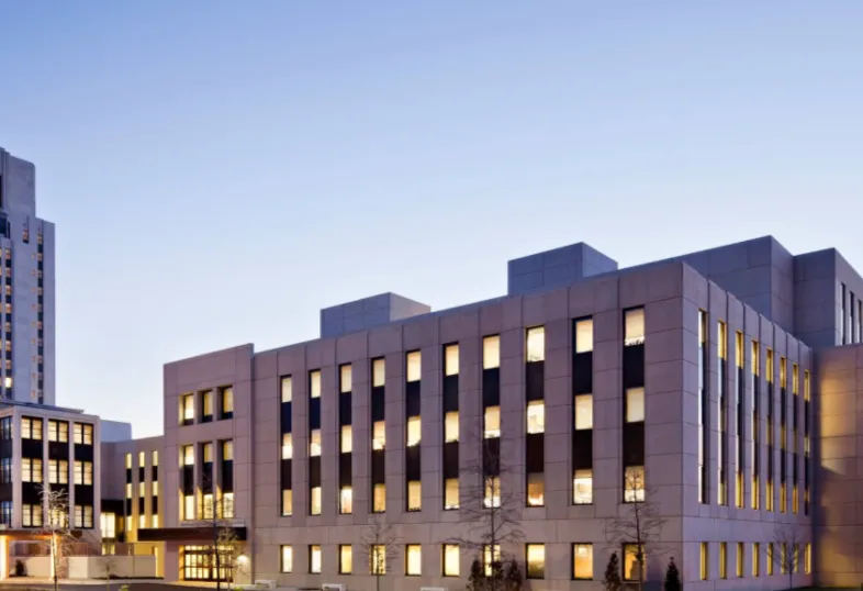 Modern multi-story office building with numerous illuminated windows at dusk.