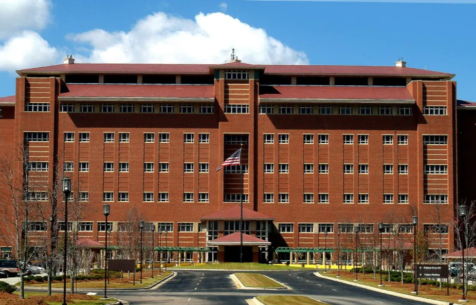 Large red brick institutional building with multiple windows and an American flag in front.
