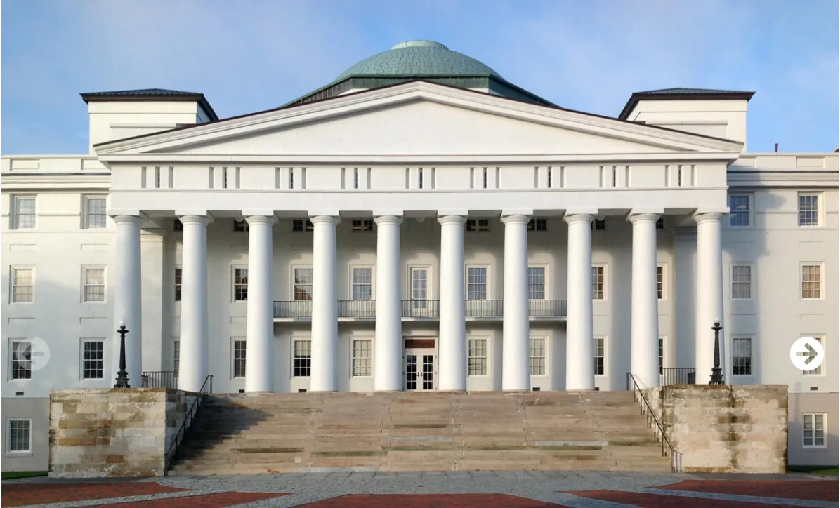 Front view of a large white neoclassical building with tall columns and a green dome.