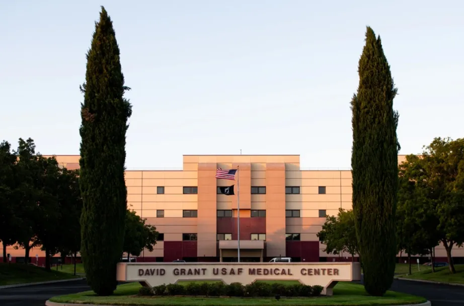 Exterior view of David Grant USAF Medical Center with American and POW flags.
