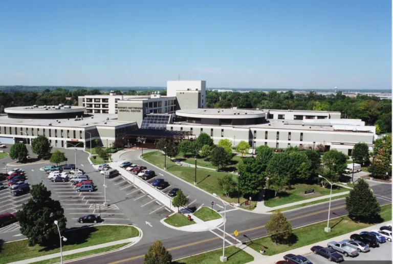 Aerial view of Wright-Patterson Medical Center surrounded by parking lots, trees, and roads under a clear blue sky.