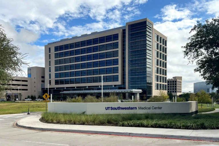 UT Southwestern Medical Center multi-story building with glass windows under partly cloudy sky.