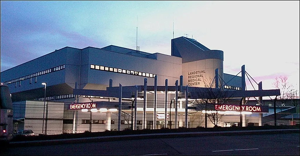 Exterior view of Landstuhl Regional Medical Center at dusk with illuminated emergency room signs.