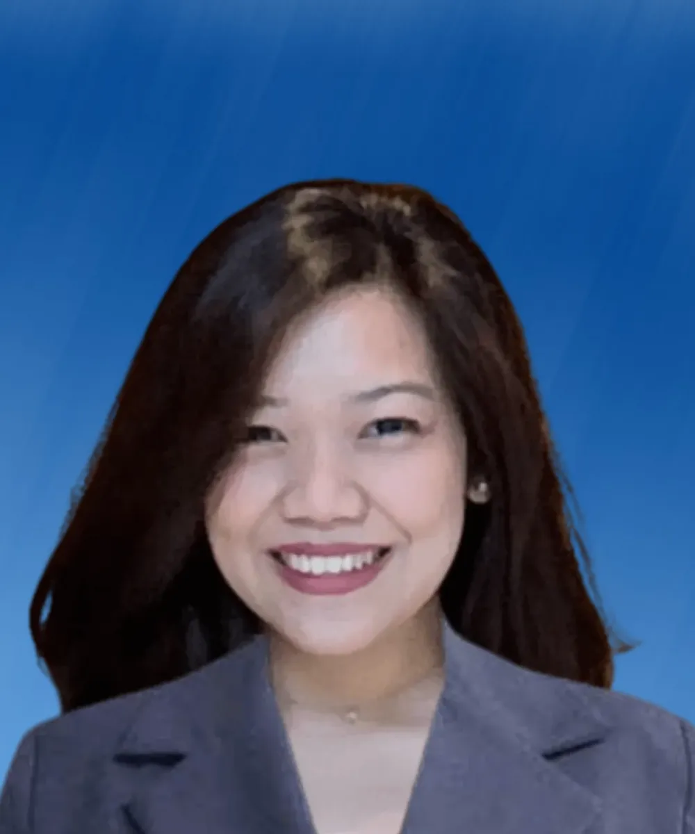 Professional headshot of a smiling woman with long dark hair wearing a gray blazer, blue background.