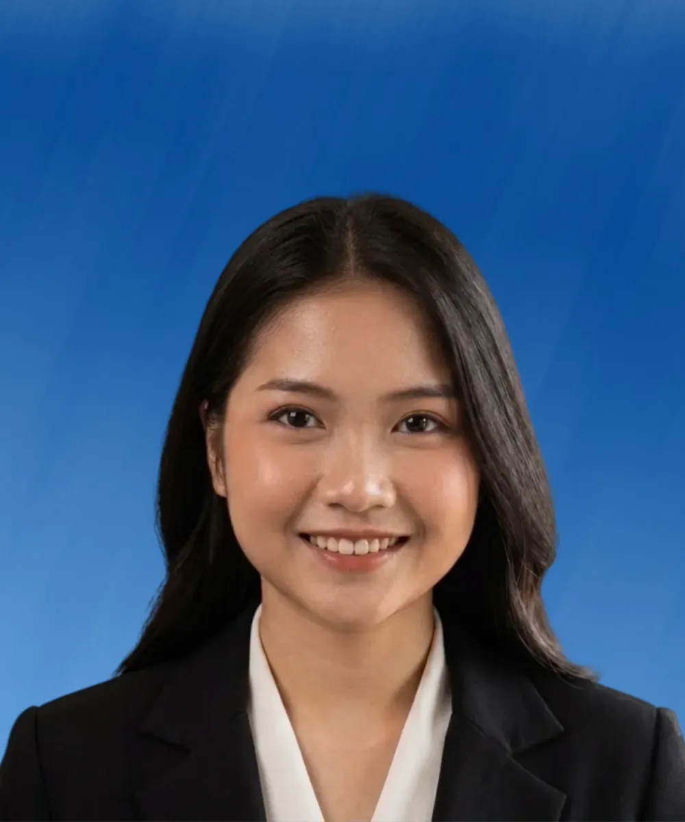 Professional headshot of a smiling woman with long dark hair, wearing a black blazer and white blouse, against a blue background.