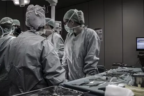Surgical team in sterile gowns and masks preparing for operation in operating room.