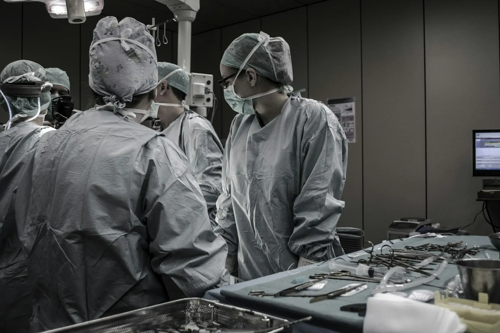 Medical professionals in surgical attire preparing instruments in an operating room.