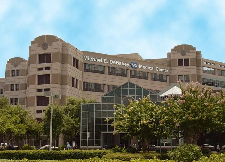 Exterior view of Michael E. DeBakey VA Medical Center building with trees and greenery in foreground.