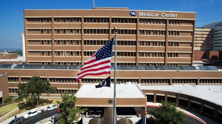 Exterior view of VA Medical Center building with American and POW flags in foreground.